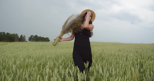 Girl In A Straw Hat Walks On A Wheat Field