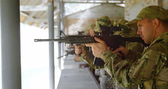 Side view of mixed-race military soldiers shooting rifle in target practice during training 4k