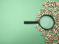 Wooden word and magnifying glass on a green background - PhotoDune Item for Sale