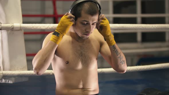 Box Training - a Man Sitting on the Ring - Putting on Headphones and Gloves