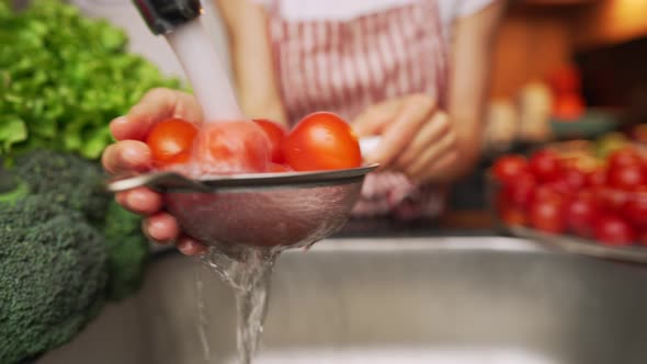 Female Hands Washing a Tomatos Under a Stream of Water at the Kitchen