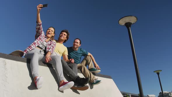 Happy caucasian woman and two male friends taking selfie