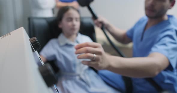 Autistic Girl undergoing TMS treatment for the brain in a clinic by a male nurse