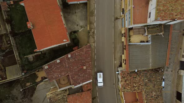 Overhead shot of a village road with some cars passing by