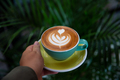 Woman holding green mug of cappuccino with latte art. - PhotoDune Item for Sale