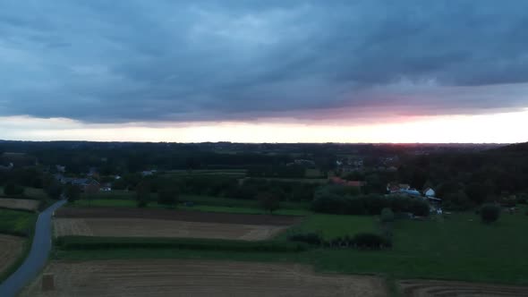 Rural landscape with agriculture fields with stormy clouds and golden sunset in horizon, aerial view