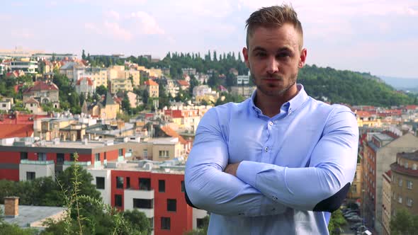 Young Handsome Business Man Looks To Camera with Self-confident Face - City in Background