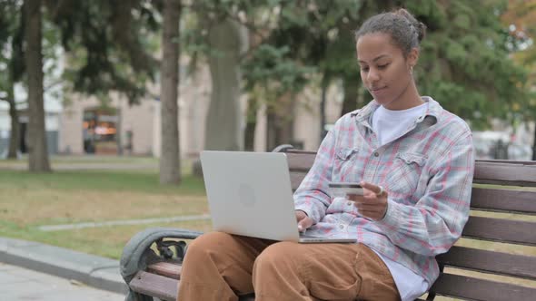 African Woman Frustrated By Online Shopping Failure While Sitting Outdoor on Bench