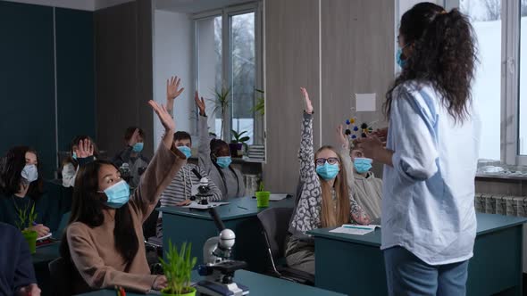 Active Masked Students Raising Hands During Lesson