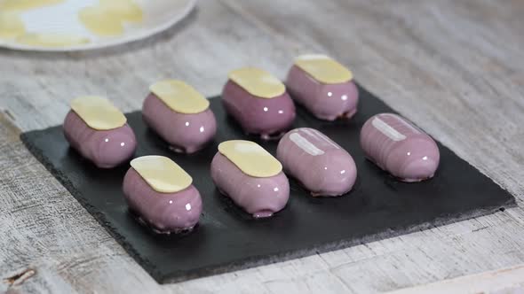 Preparing modern, french desserts - mousse with purple mirror glaze. Decorate french mousse cakes	