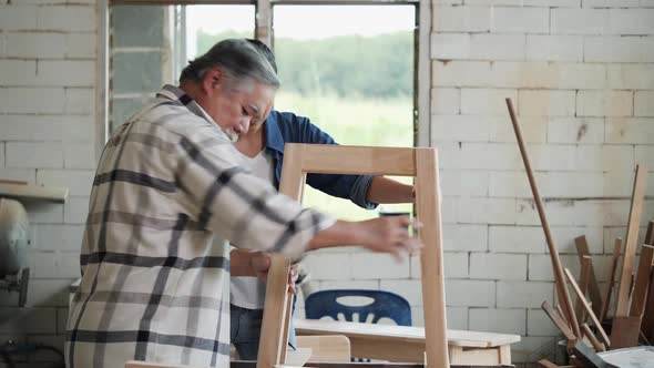 Senior man and young woman fit wood together