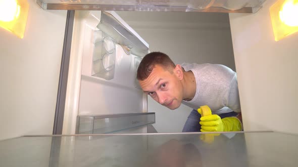 the man opens the refrigerator, sniffing and plugging his nose