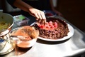 Candid Lifestyle Photo of a Young a Girl decorating a Chocolate Cake with Fresh Red Raspberry - PhotoDune Item for Sale