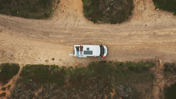 Two men lays on top of van drone shot zooming out