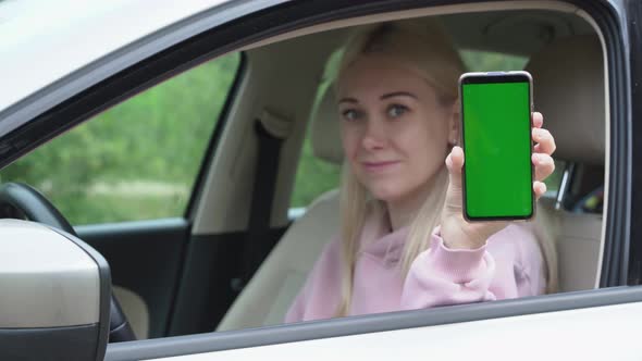 Woman scratching a phone in her hands while sitting in a car