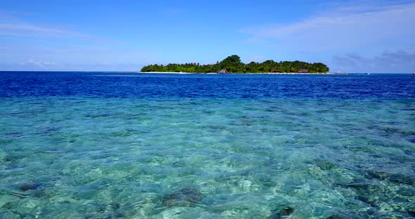 Beautiful flying tourism shot of a white paradise beach and blue water background in best quality 4K