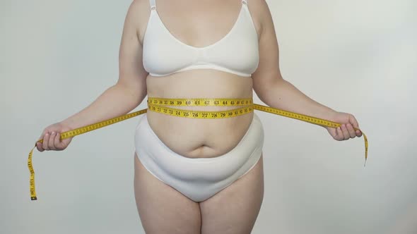 Obese Woman Measuring Her Waist in White Lingerie, Motivation and Dieting