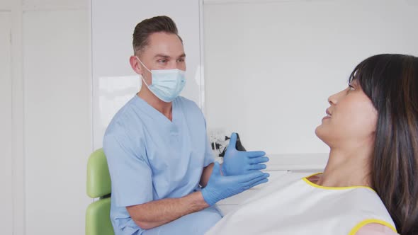 Caucasian male dentist with face mask preparing smiling female patient at modern dental clinic