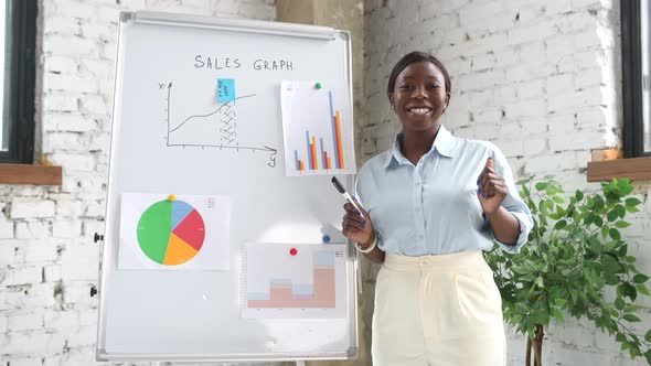 Intelligent African American Woman in Smart Casual Wear Stands Near Whiteboard