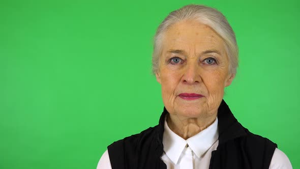 An Elderly Woman Looks Seriously at The Camera