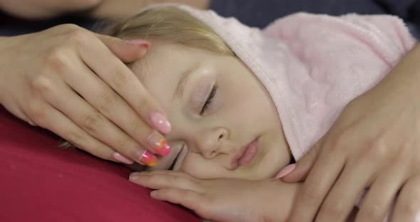 Young Mother Taking Care of Her Little Baby Girl While She Sleep. Girl on Bed