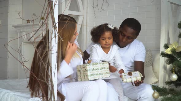 Happy Family Opening Their Christmas Presents Together. Young Happy Multi-ethnic Family of Mother