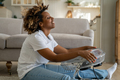 Happy young black woman sits in front of fan at home cooling down at home after being in heat - PhotoDune Item for Sale