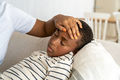 Sick unhealthy black child small boy lies with closed eyes near mom touch forehead check temperature - PhotoDune Item for Sale