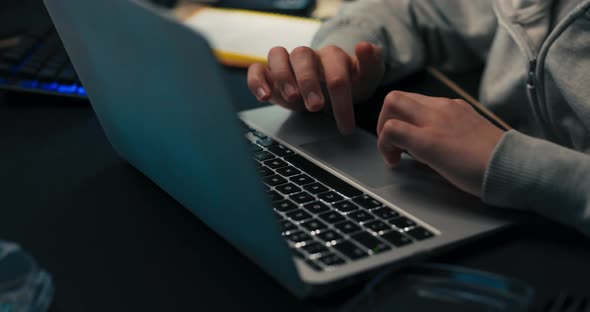 A Teenager with Curly Hair and Headphones on Head Sits at a Desk in a Dark His Bedroom