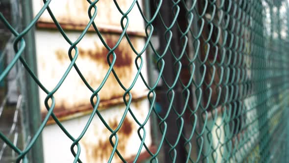 Fence mesh netting close up and iron rusty white wall in blur