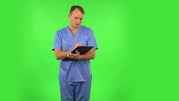 Medical Man Fills Papers at Black Folder with Pensil. Green Screen
