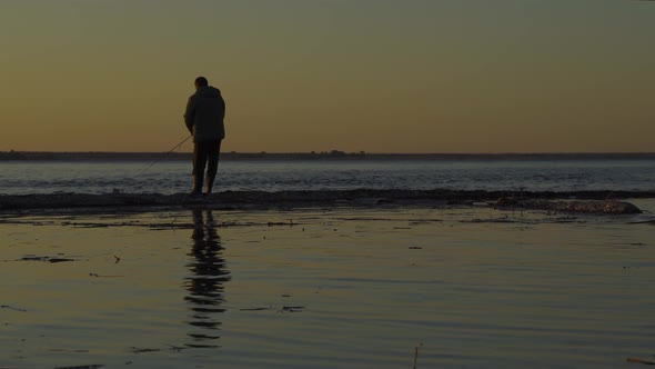 A Man Fisherman Catches Fish at Dawn on the Spit of a Large Reservoir. Fishing on the Volga River