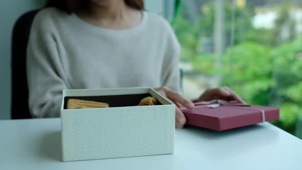 Closeup of a young woman opening a red present box