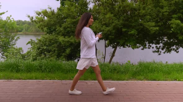 Young Woman Typing Message on Mobile in City Park