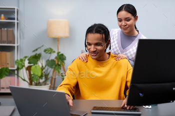 Two young people reviewing code together using compiter