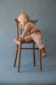  Portrait Cute one year old baby girl, wearing brown suit, sitting on a wooden chair. - PhotoDune Item for Sale
