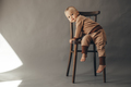  Portrait cute one year old baby girl, wearing brown suit, sitting on a wooden chair - PhotoDune Item for Sale