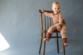 Portrait cute one year old baby girl, sitting on a wooden chair. - PhotoDune Item for Sale