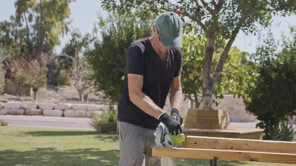 Slow motion of a man using a round saw to cut through wood