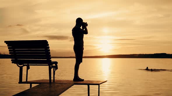 Photographer taking picture of landscape during sunset