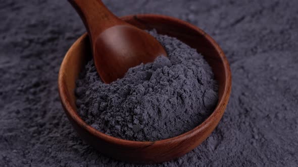 blue butterfly pea powder in wooden bowl close up, rotating