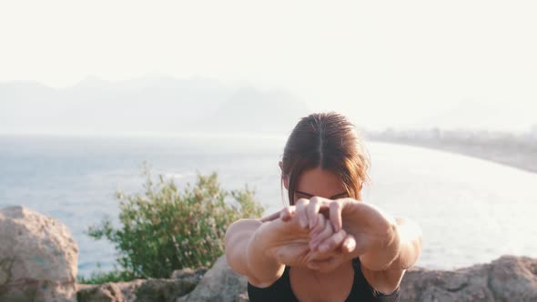 Sportive Woman Stretching Her Hands on the Hill By the Sea