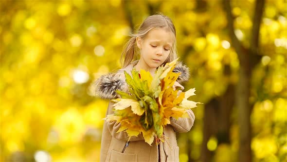 Portrait of Adorable Little Girl with Yellow Leaves Bouquet in Fall. Beautiful Smiling Kid Lying on