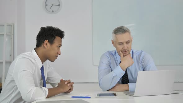 African and Grey Hair Businessman Discussing Project on Laptop