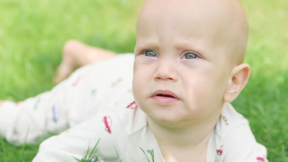 Funny Baby Child Lying on Green Grass Garden Making Face Smiling Exploring