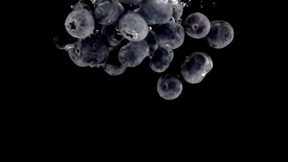 Super slow motion, a pile of blueberries fall into the water