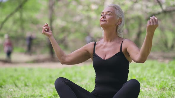 Confident Caucasian Senior Yogi Sitting in Lotus Pose Meditating Outdoors