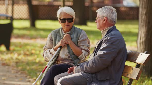 Blind Elderly Woman Sitting on the Bech with Her Husband