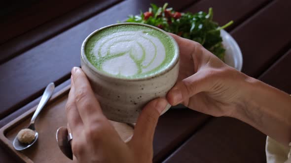 Human Hands Holding Hot Green Matcha Latte Cup Healthy Dietary Lunch with Trendy Vegan Avocado Toast