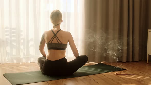 Woman doing yoga and meditating, practicing yoga at home in the morning